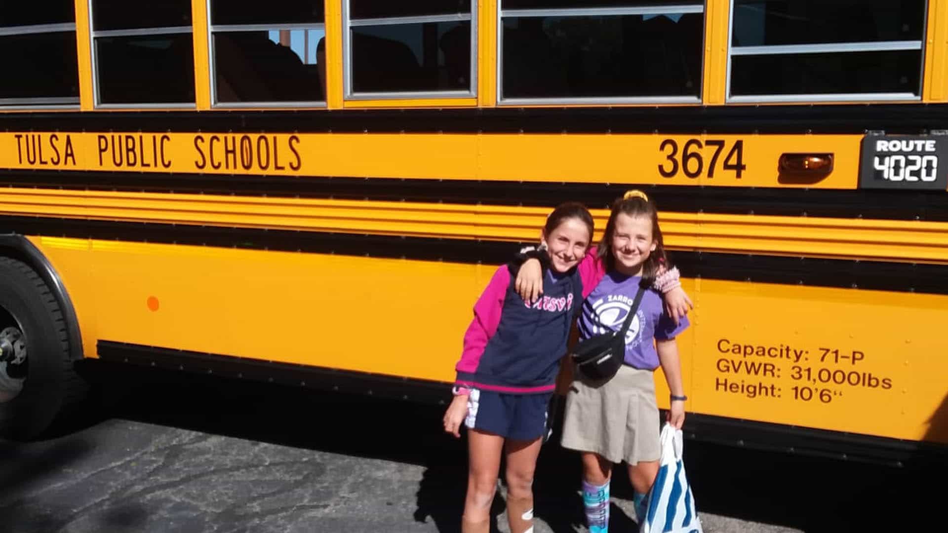 Dos alumnas de Casvi posan delante de un autobús americano de Tulsa.