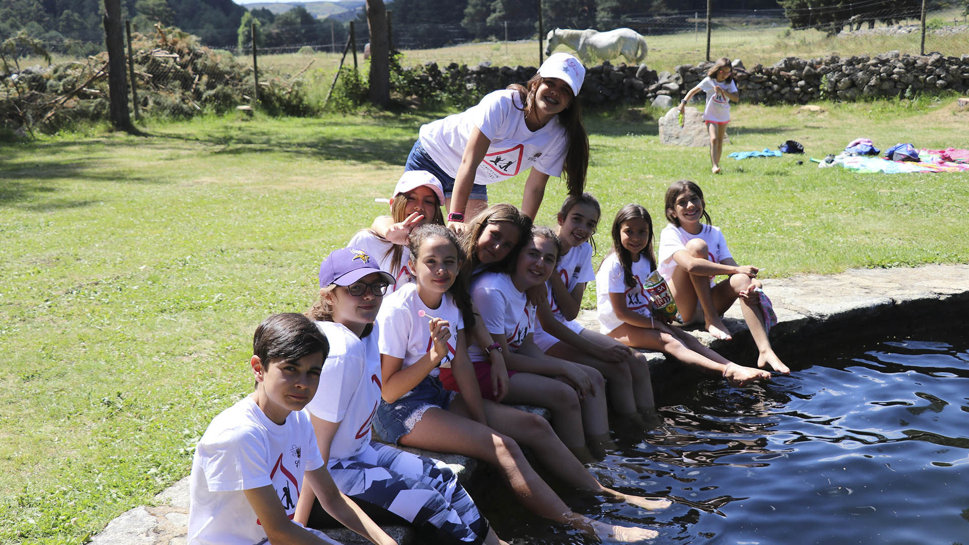 Alumnos posan en unas piscinas naturales con un caballo de fondo en los Campamentos de Verano en inglés Casvi.